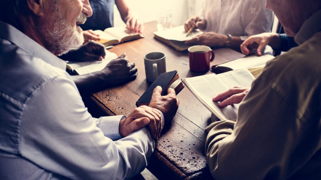 hands together praying at a table