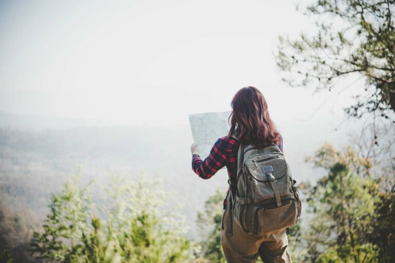 Woman hiking on a mountain range looking at a map